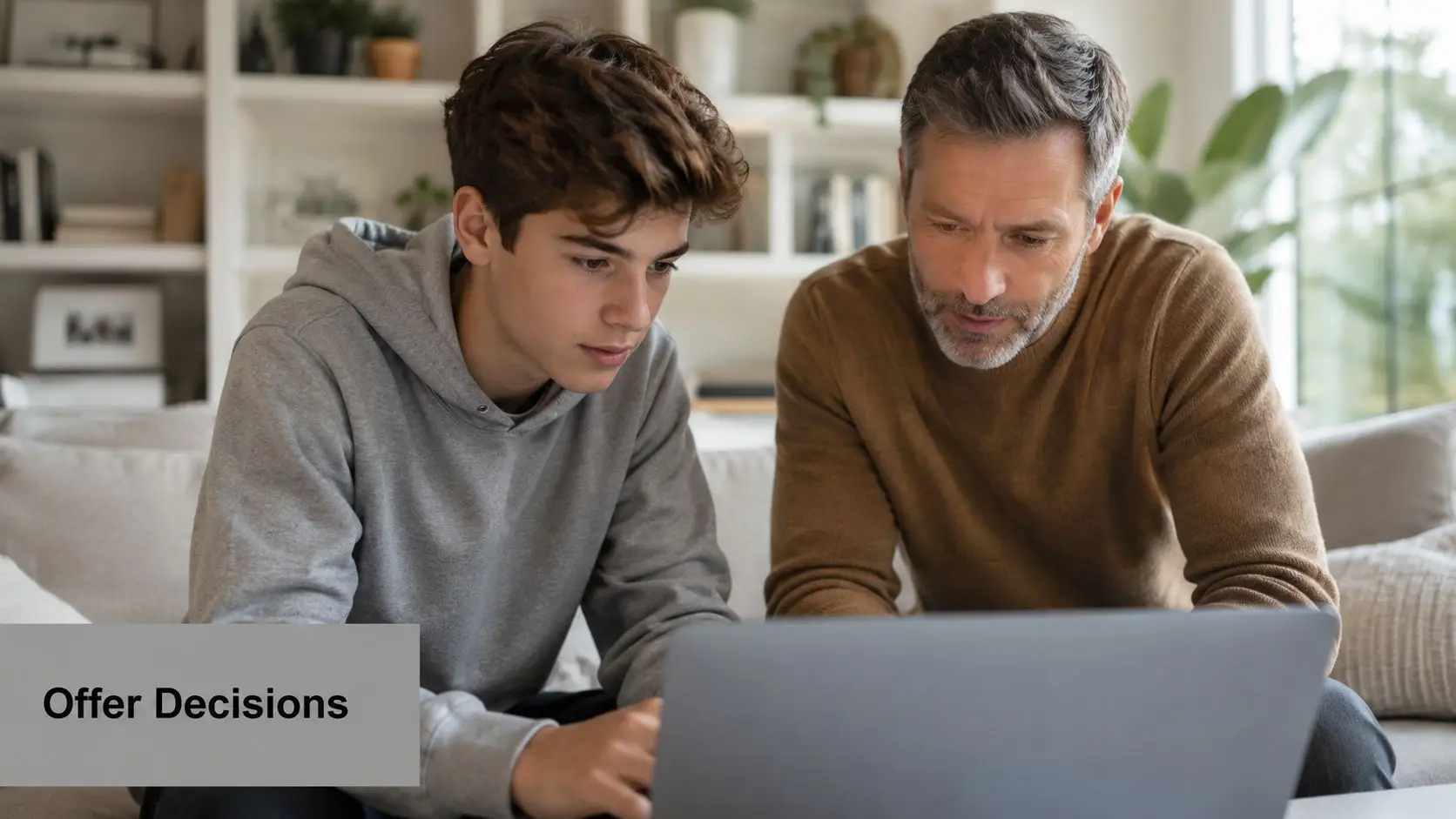 A father and son sitting on a sofa looking at a laptop during the ucas application process.