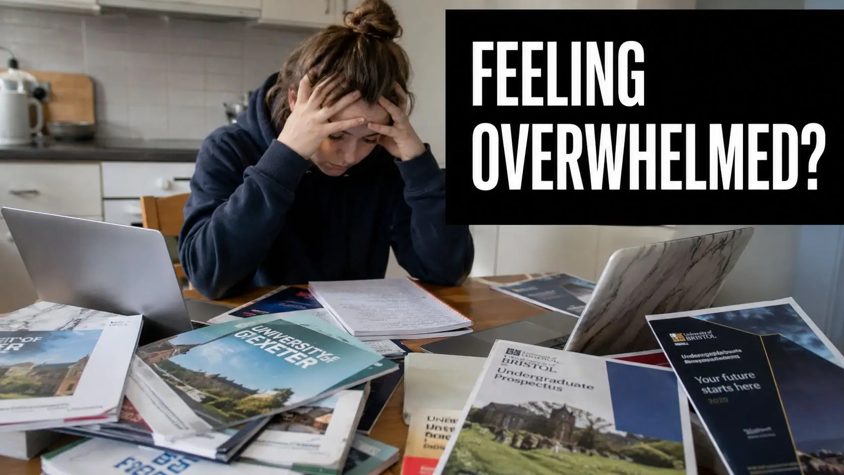 A stressed student sitting at a table surrounded by university prospectuses and laptops while looking overwhelmed.