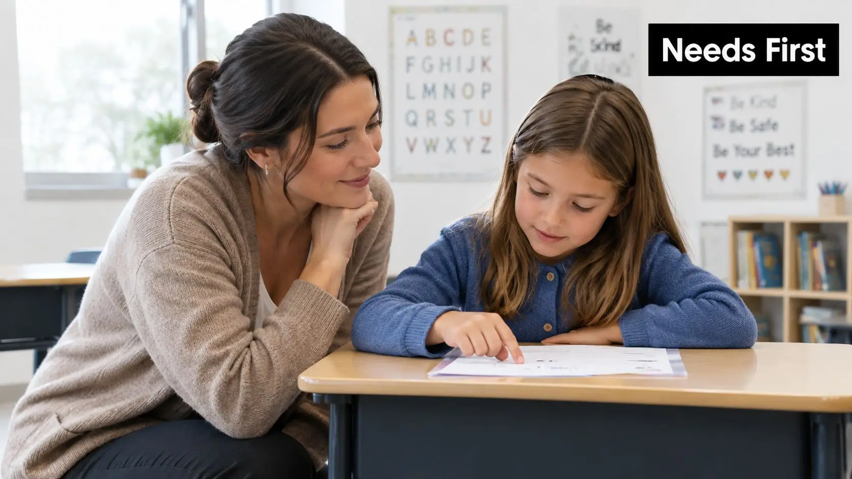 A teacher gently guides a young female student with her schoolwork at a desk in a classroom.